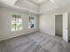 Spacious bedroom featuring neutral carpet and paint, two windows letting in natural light, and a tray ceiling at 6260 Selborn Sw Dr, Atlanta, GA 30331
