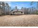 Large, private backyard with dormant grass, mature trees and a view of the home's rear elevation at 1791 Lake George Dr, Lithia Springs, GA 30122
