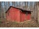 Red wooden outbuilding surrounded by dormant foliage, showcasing a rustic structure at 1791 Lake George Dr, Lithia Springs, GA 30122
