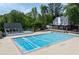 Large community pool surrounded by lush greenery, sun deck, and shaded seating areas at 220 Galesburg Dr, Lawrenceville, GA 30044