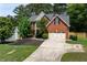 Charming two-story brick home featuring a manicured lawn, mature trees, and a two-car garage at 220 Galesburg Dr, Lawrenceville, GA 30044