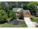 Traditional brick home featuring a manicured lawn, mature trees, and a two-car garage at 220 Galesburg Dr, Lawrenceville, GA 30044