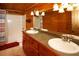 Rustic bathroom featuring double sinks, wooden paneling, and a tub/shower combo at 1225 Pitts Chapel, Newborn, GA 30056