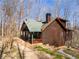 Exterior shot showing log cabin home, with stone chimney, front porch and landscaped yard at 1225 Pitts Chapel, Newborn, GA 30056