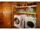 This rustic laundry room features a washer, dryer, wood walls, and ample storage shelves at 1225 Pitts Chapel, Newborn, GA 30056