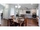 Open dining area with wood floors, chandelier lighting, and open floor plan to living room with large screen TV at 1570 Shire Village Dr, Sugar Hill, GA 30518