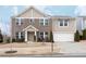 Charming two-story brick home with a well-manicured lawn and attached two-car garage in a suburban neighborhood at 1570 Shire Village Dr, Sugar Hill, GA 30518