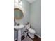 Cozy half bathroom features a pedestal sink, decorative mirror, and tiled floors at 1570 Shire Village Dr, Sugar Hill, GA 30518