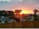 A colorful sunset seen beyond the backyard fence and neighborhood at 1570 Shire Village Dr, Sugar Hill, GA 30518