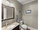 Half bathroom featuring granite countertop sink, toilet, modern faucet and a decorative framed mirror at 194 Sentinel Se Pl, Marietta, GA 30067