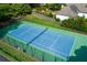 Aerial view of fenced tennis court with blue and green surface, adjacent to manicured lawns and a home at 2622 Murdock Rd, Marietta, GA 30062