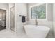 Bright bathroom features glass-enclosed shower, standalone tub, and marble floors at 5008 Monticello Dr, Villa Rica, GA 30180