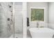 Bright bathroom features glass-enclosed shower and standalone tub with a window at 5008 Monticello Dr, Villa Rica, GA 30180