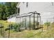 Backyard greenhouse featuring a black metal frame and raised garden beds with lush plants and greenery at 5008 Monticello Dr, Villa Rica, GA 30180