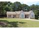 Charming brick home with manicured lawn, mature trees, and a welcoming red front door at 1311 N Brandy Se Shls, Conyers, GA 30013