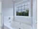 Bright bathroom features a soaking tub with jets and tiled wall with a large window at 1847 Oak Rd, Snellville, GA 30078
