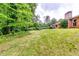 Wide view of the backyard with a gentle slope, lush greenery, and the house nestled amidst the trees at 2668 Kings Park Cir, Decatur, GA 30034
