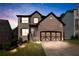 Evening view of a two-story brick home featuring a two-car garage, and landscaped front yard at 456 Crestmont Ln, Canton, GA 30114