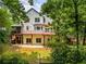 Shot of a two-story home's backyard with a wooden deck and patio amongst the wooded area at 710 Devon Hill Ct, Roswell, GA 30075