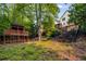 View of a two-story home's backyard with a wooded area and a charming wood playhouse for the  at 710 Devon Hill Ct, Roswell, GA 30075