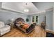 Bright bedroom featuring hardwood flooring, tray ceiling, and large bed at 710 Devon Hill Ct, Roswell, GA 30075