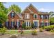 Stately brick home featuring a symmetrical facade, manicured lawn, and charming blue shutters at 710 Devon Hill Ct, Roswell, GA 30075