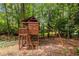 Outdoor wood playhouse with a swing set and climbing ladder set back in a lush, shady yard at 710 Devon Hill Ct, Roswell, GA 30075