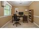 Staged tan office with tile floors includes a desk, chair, computer, art and bookcase at 5697 Brooklyn Ln, Norcross, GA 30093