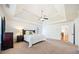 Bright main bedroom features a tray ceiling, fan, and neutral-toned carpet and walls at 8360 Village School Dr, Cumming, GA 30041