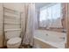 Bathroom with a white toilet, tub with shower curtain, pink tile and shelving unit at 2485 Shady Shoals Ct, Decatur, GA 30034