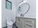 Stylish powder room with black and white accent tiles, wood cabinet and round mirror at 106 Belmont Dr, Canton, GA 30115