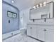 Modern bathroom featuring blue accent wall, glass shower, double sink vanity, black hardware, and marble floor at 106 Belmont Dr, Canton, GA 30115