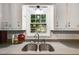 Stainless steel kitchen sink under a window overlooking a lush green landscape at 230 King Arthur Dr, Woodstock, GA 30189