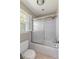 Bright bathroom featuring a shower over bath with sliding glass door and window at 2785 Fontainebleau Dr, Dunwoody, GA 30360