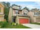 This two-story home boasts a red garage door, green trim, and is set on a well-manicured lawn at 6571 Splitpine Ct, Atlanta, GA 30349
