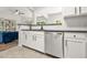 Modern kitchen with white cabinetry and stainless steel dishwasher, open to living room at 6571 Splitpine Ct, Atlanta, GA 30349