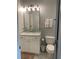 Small bathroom with a toilet, sink, cabinet, mirror and stylish fixtures at 970 Tarpley Nw Rd, Kennesaw, GA 30152