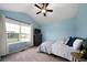 Bright bedroom featuring blue walls, large window, ceiling fan, and neutral carpet at 137 Cambridge Pointe, Villa Rica, GA 30180