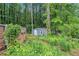 Backyard view of a home's exterior, with small outbuildings surrounded by lush, overgrown landscaping at 2549 Emerald Dr, Jonesboro, GA 30236