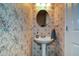 Charming powder room featuring floral wallpaper, a pedestal sink, oval mirror, and modern fixtures at 49 Timberlake Ne Cv, Cartersville, GA 30121