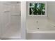 Bathroom with a window view, featuring a shower stall and a large soaking tub at 575 Freeman Dr, Covington, GA 30016