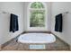 Close-up of a soaking tub featuring decorative window, granite surround, and towel bars on either side at 1255 Beech Haven Ne Rd, Atlanta, GA 30324