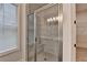 Luxurious glass shower with marble-look tile, built in seat, and light fixture, with a peek into the walk in closet at 2505 Whistler Way Ne, Lawrenceville, GA 30043
