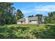 View of the back of the house with a large lawn, trees, and blue skies at 267 Rocky Point Rd, Covington, GA 30014