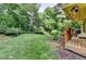Green backyard with a wood deck, barbecue grill, and lush greenery at 1486 Maple Ridge Dr, Suwanee, GA 30024