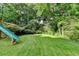 Lush green backyard featuring grass, trees, and green slide at 1486 Maple Ridge Dr, Suwanee, GA 30024