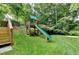 Grassy backyard features a wood playground with a green slide, trees, and stairs at 1486 Maple Ridge Dr, Suwanee, GA 30024