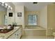 Well-lit bathroom with a garden tub, granite countertop vanity, and a window providing natural light at 1486 Maple Ridge Dr, Suwanee, GA 30024