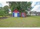 View of the backyard with lawn, trees, and painted storage sheds at 629 Birchwood Rd, Marietta, GA 30060