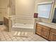 Bathroom featuring a bathtub with tile accents, a vanity, and a large mirror at 4855 West Price Rd, Sugar Hill, GA 30518